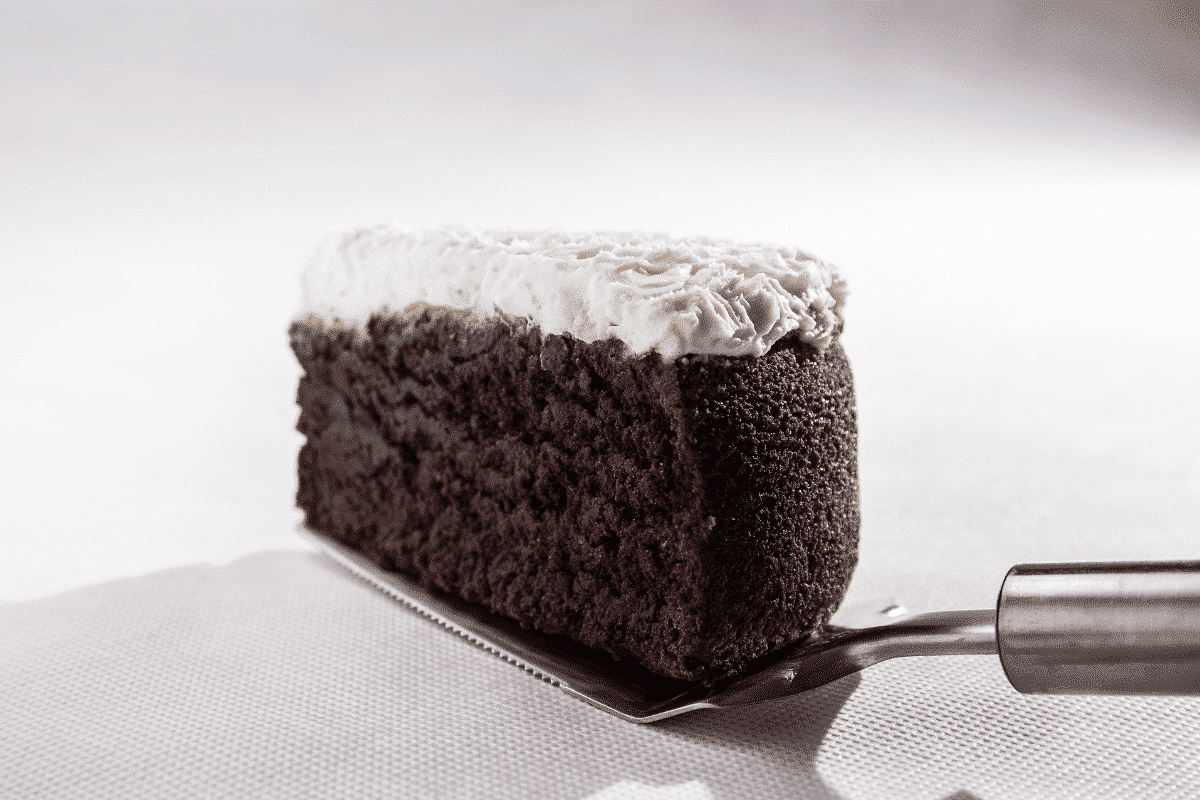 Ein Stück Guinness-Cake mit dunklem Biskuit und einer cremigen, weißen Glasur auf einem Tortenheber.