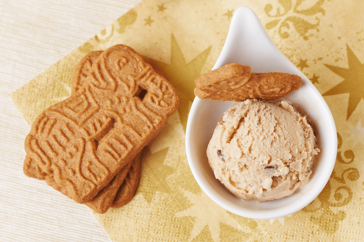 Ein Schälchen mit Karamelleis und einem Keks, daneben mehrere Keksstücke auf einem dekorativen Serviette.