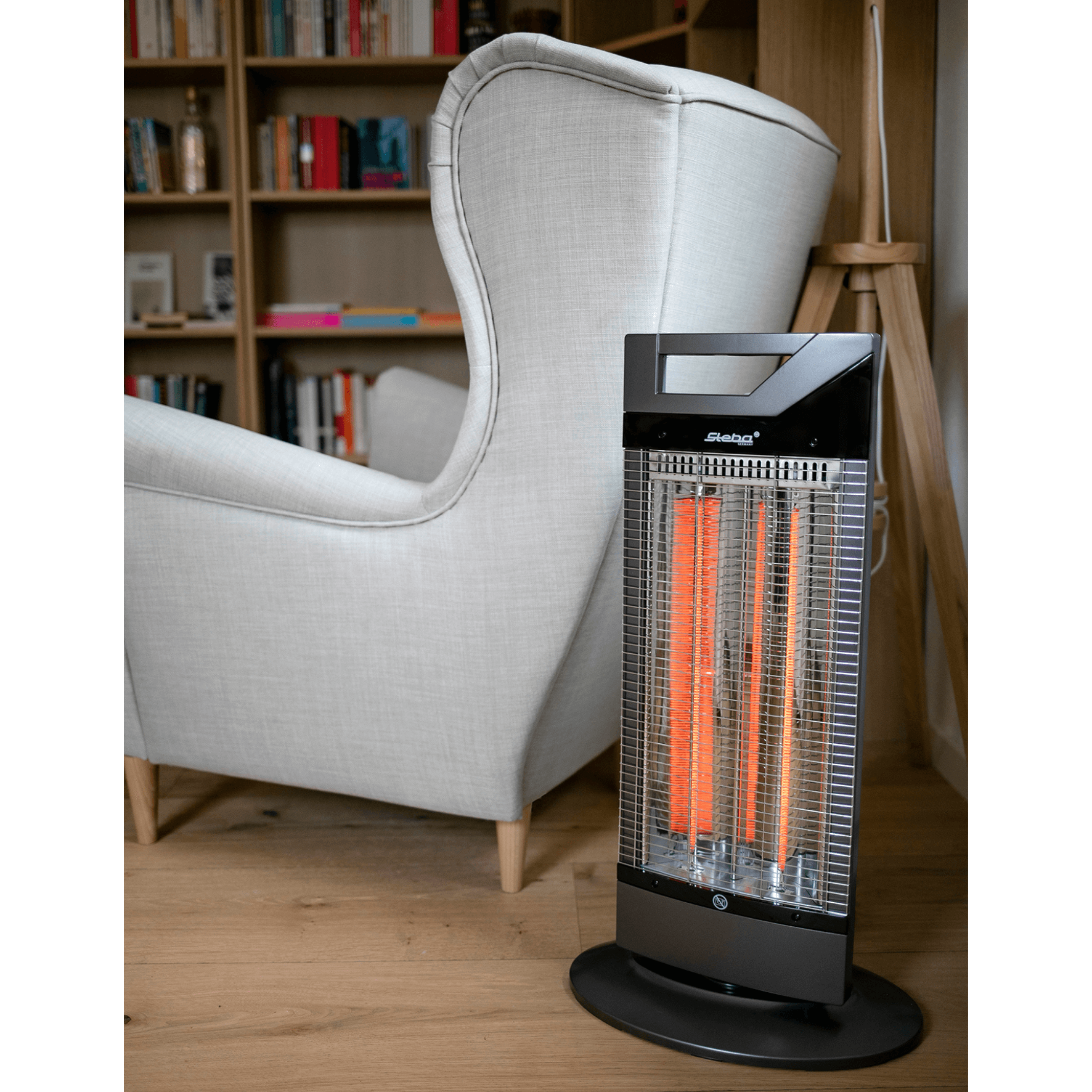 Heizstrahler von Steba mit zwei Heizröhren, schwarzer Standfuß und modernem Design, platziert neben einem Sessel.