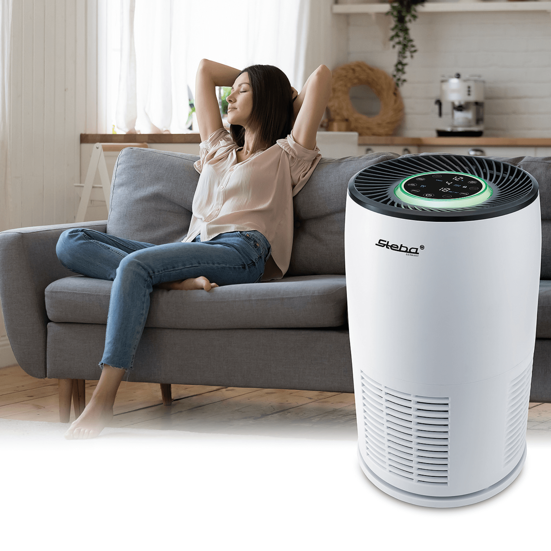 Luftreiniger Steba LR12 mit Bedienfeld und grünem Lichtring, neben einer entspannten Frau auf einer Couch.