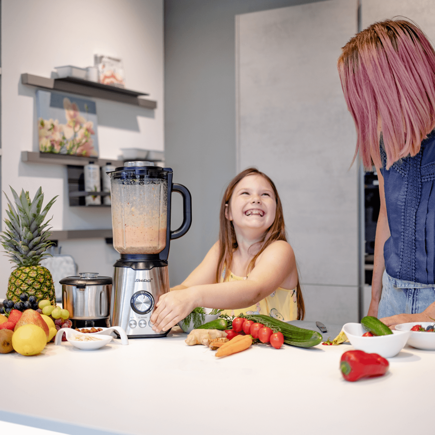 Standmixer von Steba mit transparentem Behälter, umgeben von frischem Obst und Gemüse auf einem Küchenarbeitsplatz.