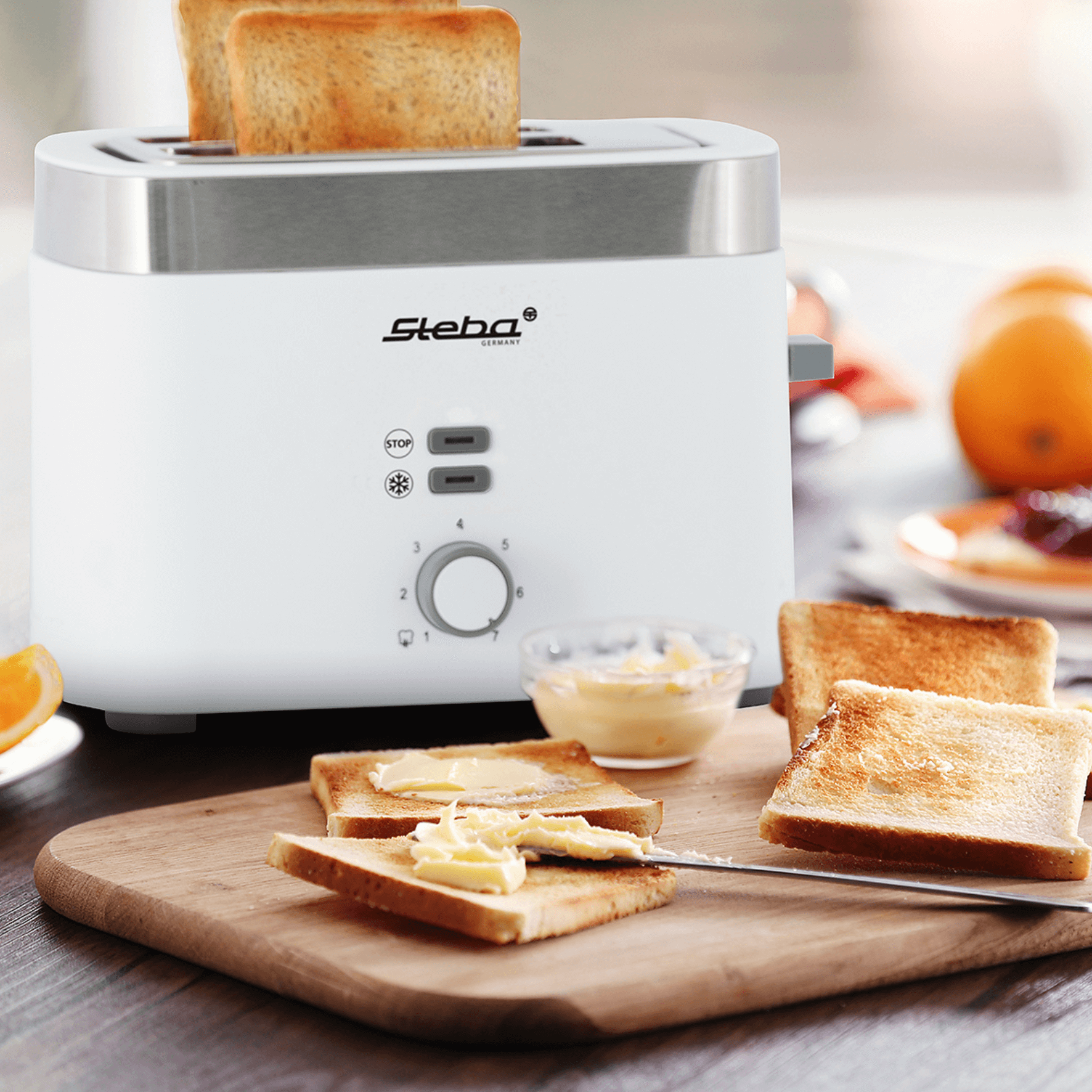 Weißer Toaster von Steba mit zwei Toastscheiben, einstellbarem Bräunungsgrad und Stopptaste, auf einem Holzbrett.