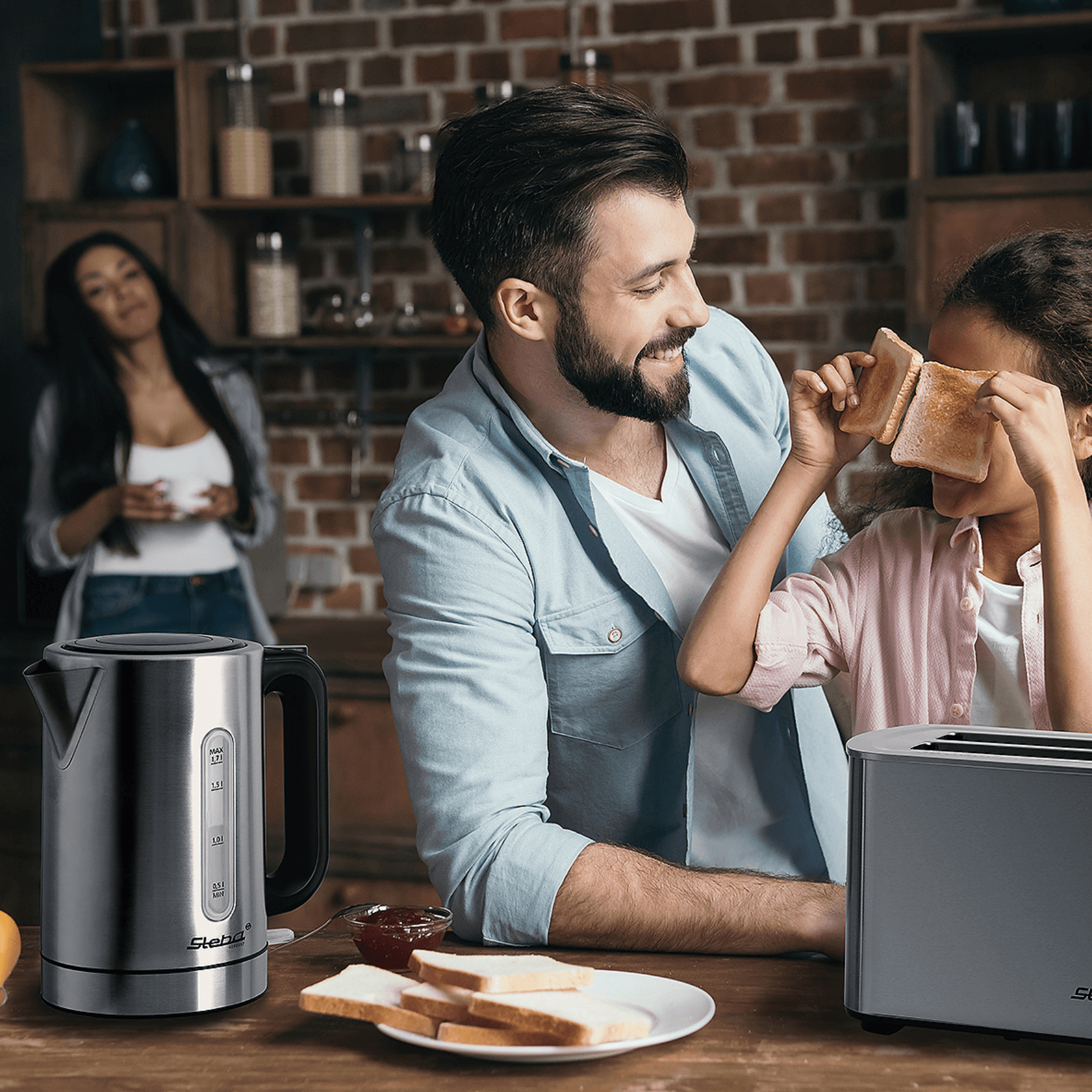 Moderne Steba Elektrogeräte in einer Küche: Wasserkocher und Toaster, während ein Vater mit seiner Tochter interagiert.
