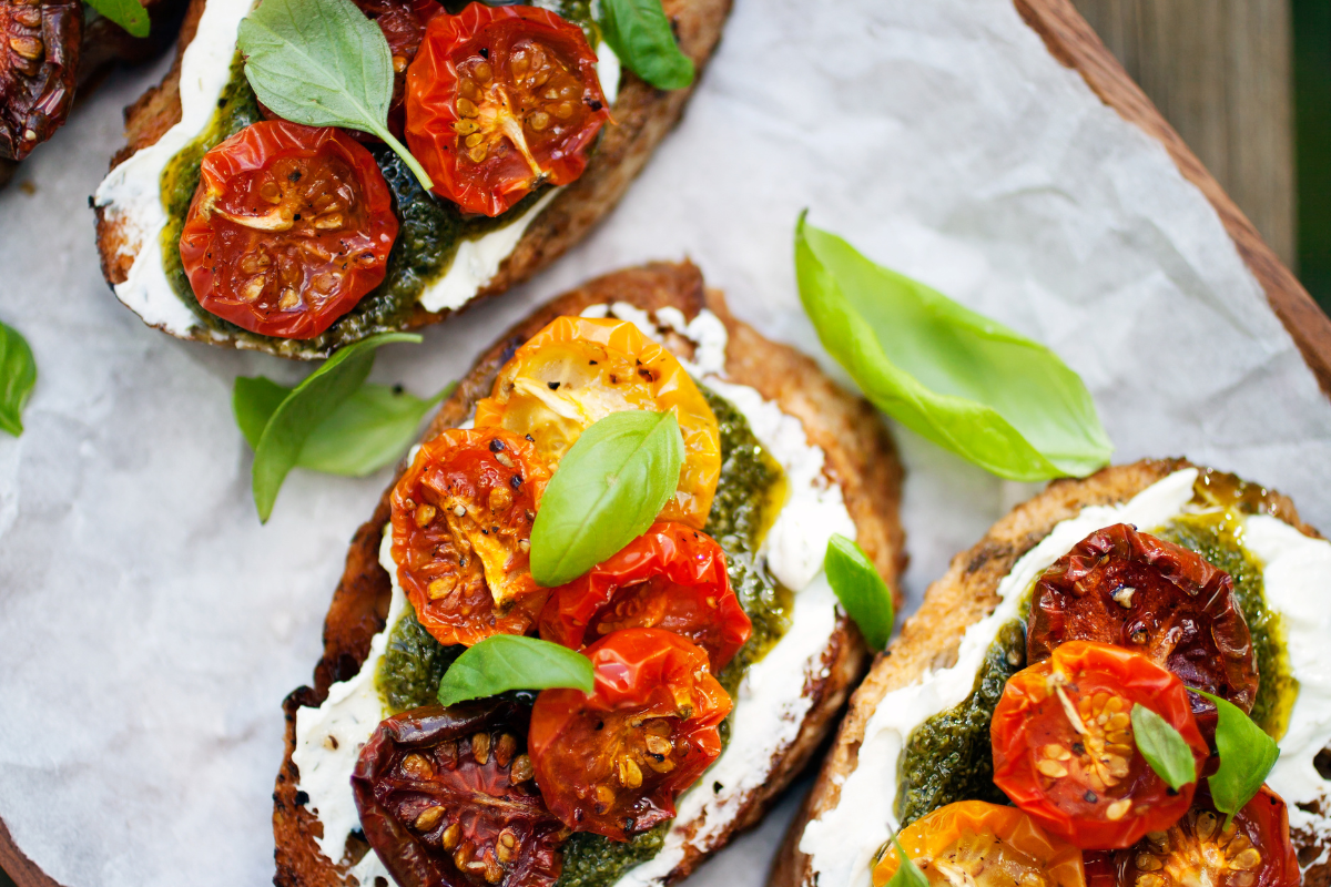 Bruschetta mit Burrata, belegt mit getrockneten Tomaten, Pesto und frischem Basilikum auf geröstetem Brot.