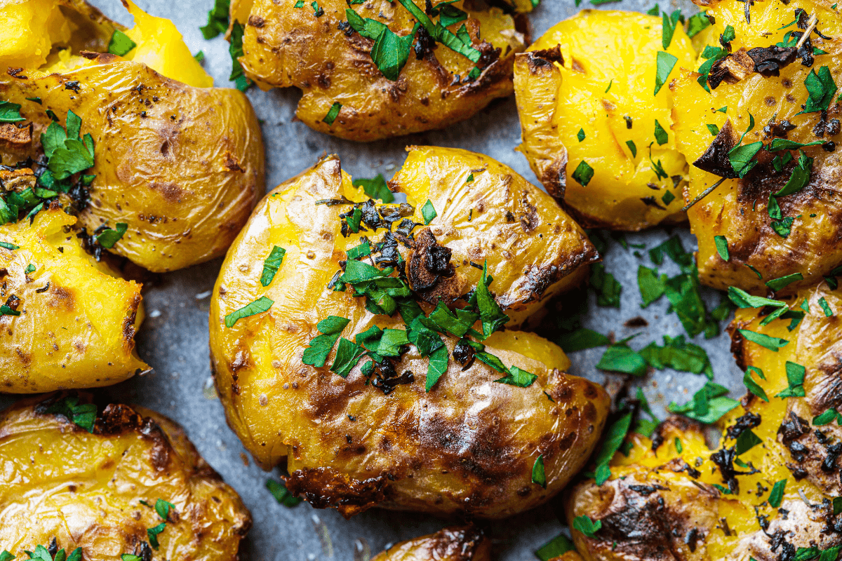 Gebackene, zerdrückte Kartoffeln mit goldbrauner Kruste und frischem, gehacktem Grün. Ideal für Beilagen.