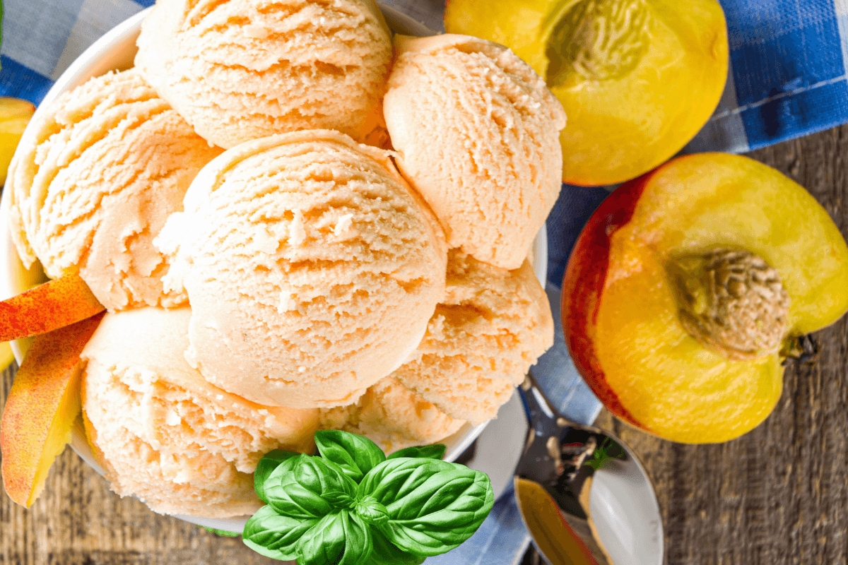 Schale mit Pfirsich-Basilikum-Sorbet, garniert mit frischem Basilikum und Pfirsichscheiben.