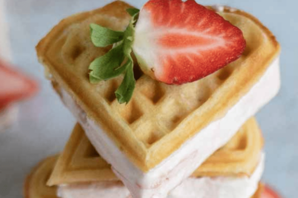 Herzförmiges Waffelsandwich mit Erdbeere und frischer Minze. Ideal für Desserts und Snacks.