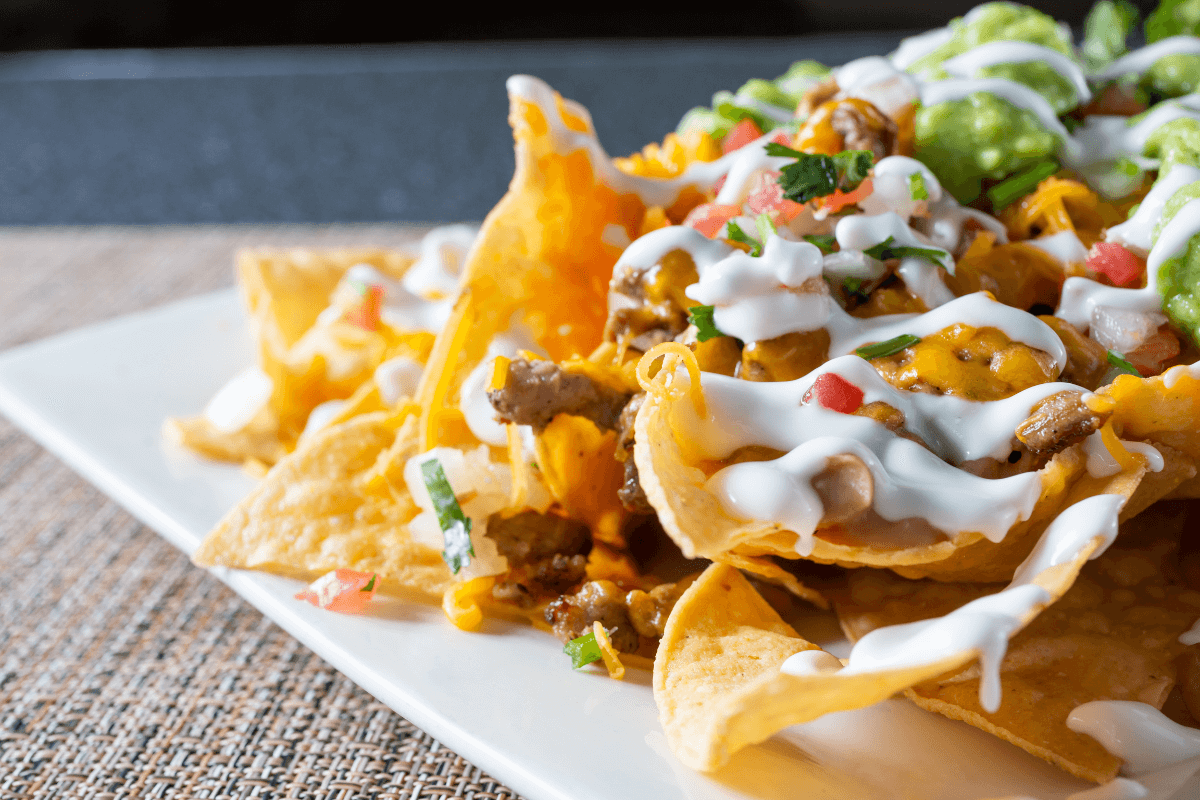 Loaded Nachos mit knusprigen Tortilla-Chips, geschmolzenem Käse, Fleisch, Pico de Gallo, Guacamole und saurer Sahne.