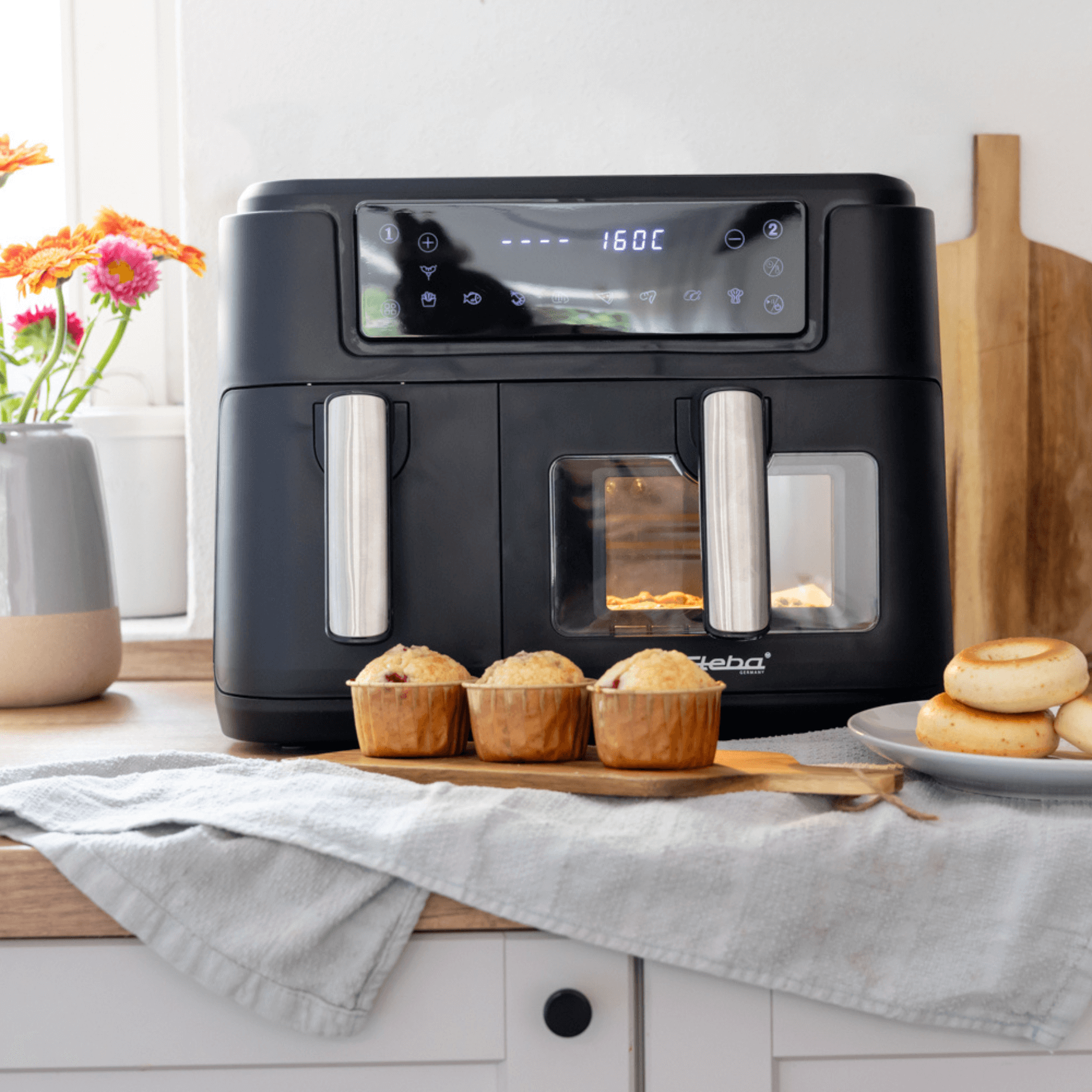 Heißluftfritteuse Steba HF9500 mit digitalem Display, zwei Frittierkammern und gebackenen Muffins im Vordergrund.