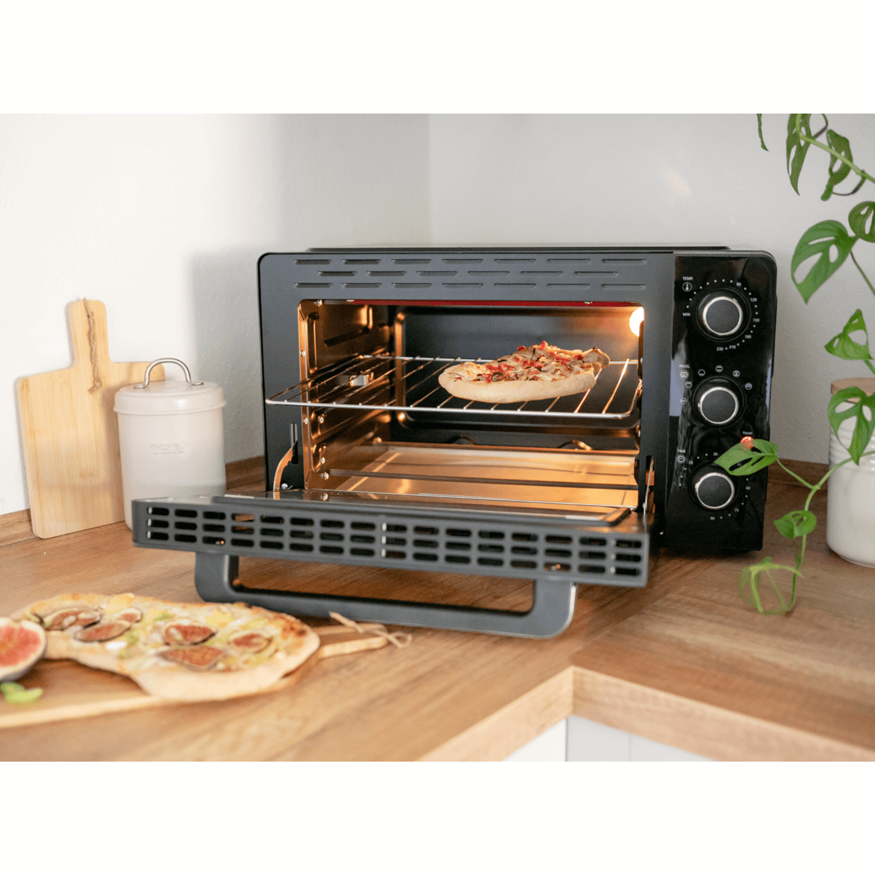 Grillbackofen Steba emo III mit Pizza auf dem Rost, platzsparend auf einer Holzoberfläche. Funktionen durch Drehregler einstellbar.