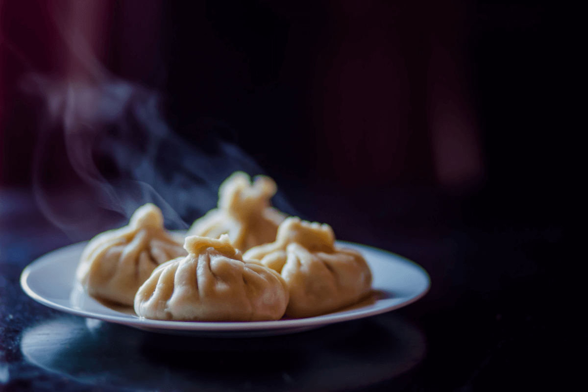 Dampfnudeln mit Gemüsefüllung auf einem weißen Teller, dampfend und appetitlich angerichtet.