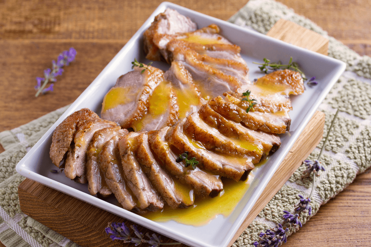 Zarte, in Scheiben geschnittene Entenbrust, serviert mit einer aromatischen Sauce, auf einem weißen Teller angerichtet.