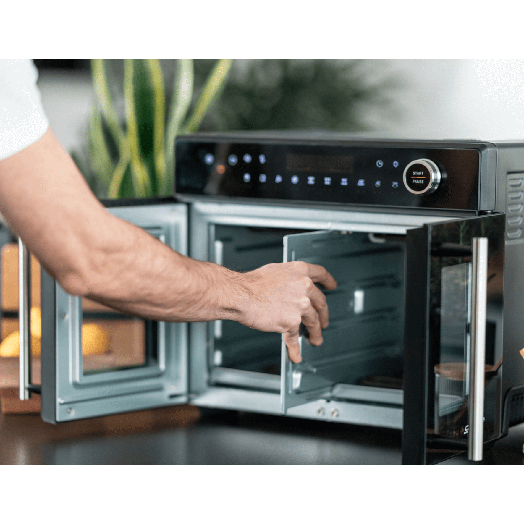 Der Steba AF24 Airfryofen mit digitalem Bedienfeld, geöffnet, zeigt eine Hand, die die Innentür öffnet.