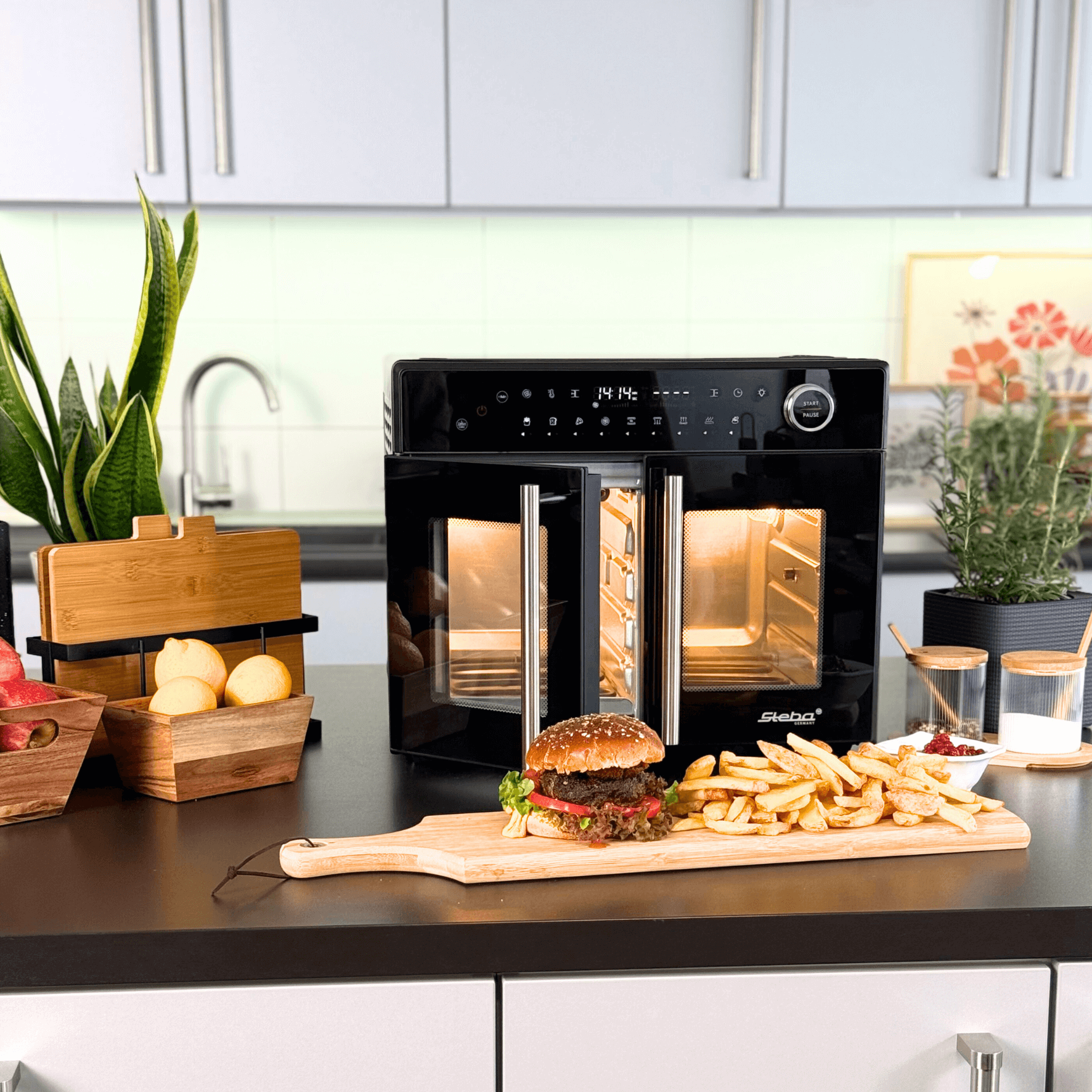 Steba AF24 Airfryofen mit doppelten Glastüren, umgeben von einem Burger und Pommes auf einem Holzbrett.